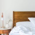 white bedspread beside nightstand with white and copper table lamp